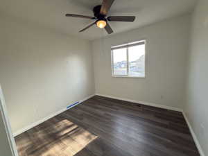 Empty room with dark wood-style flooring and ceiling fan
