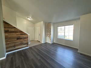 Unfurnished living room featuring dark wood-style flooring and wooden walls