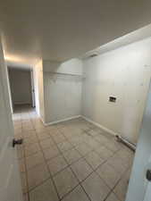 Washroom with light tile patterned floors, a textured ceiling, and washer hookup