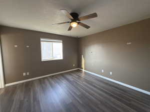 Spare room with a textured ceiling, ceiling fan, and dark wood-type flooring