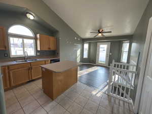 Kitchen featuring a center island, light tile patterned floors, lofted ceiling, light countertops, and ceiling fan