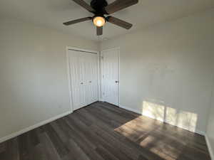 Unfurnished bedroom with dark wood-style floors, a ceiling fan, and a closet