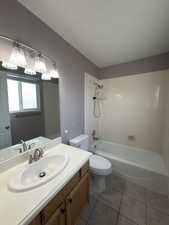 Bathroom with shower / bath combination, vanity, and light tile patterned floors