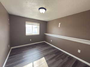 Empty room featuring dark wood-style flooring and a textured ceiling