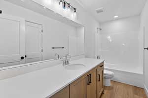 Full bath with vanity,  shower combination, light wood finished floors, and recessed lighting