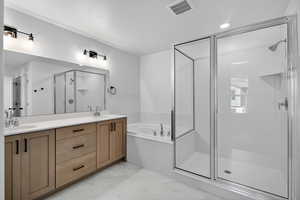 Bathroom with a shower stall, a garden tub, double vanity, light marble finish flooring, and a textured ceiling