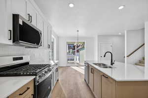 Kitchen with stainless steel appliances, recessed lighting, hanging light fixtures, light stone counters, and light wood-type flooring