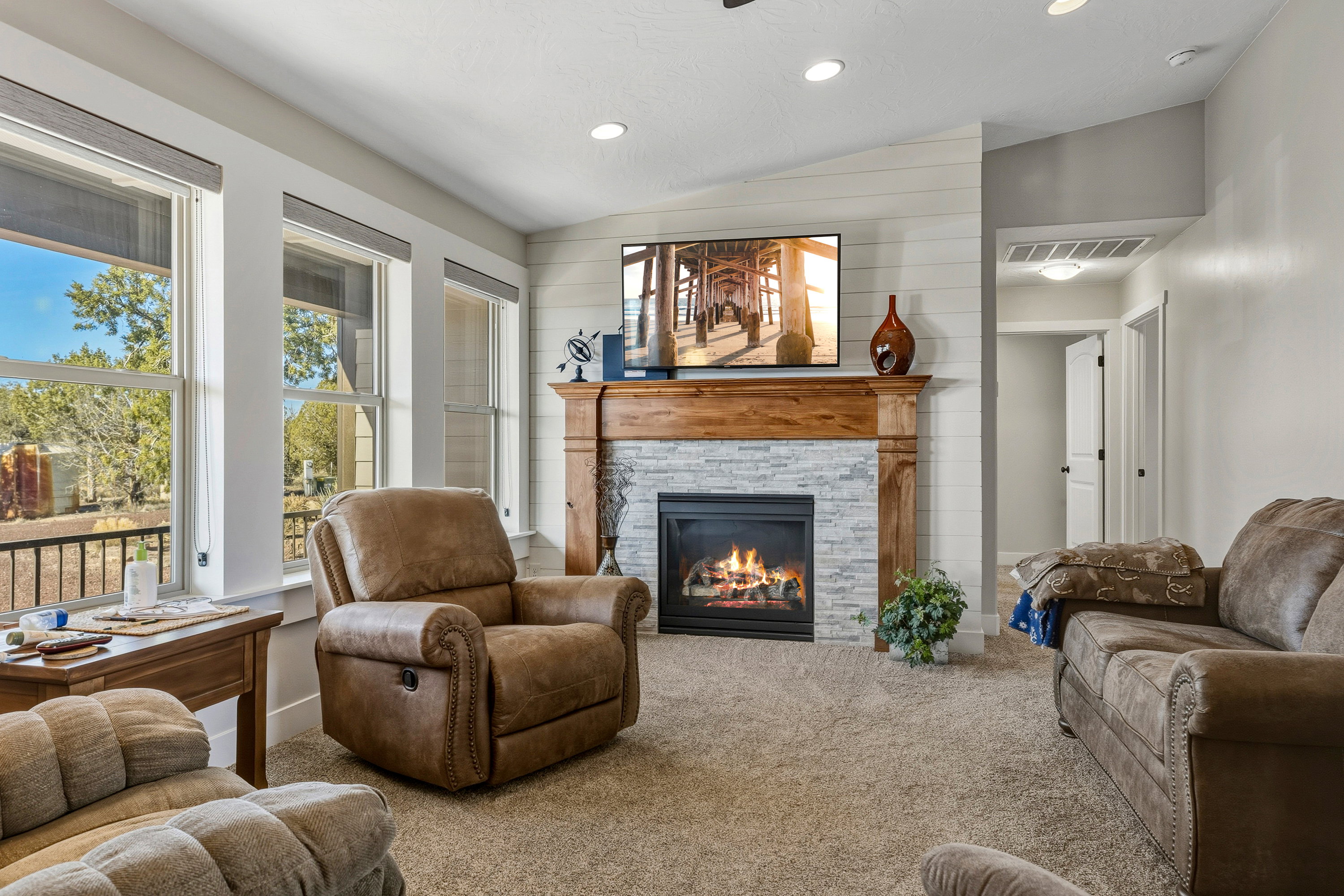 Living room with vaulted ceiling, a stone fireplace, carpet floors, and recessed lighting