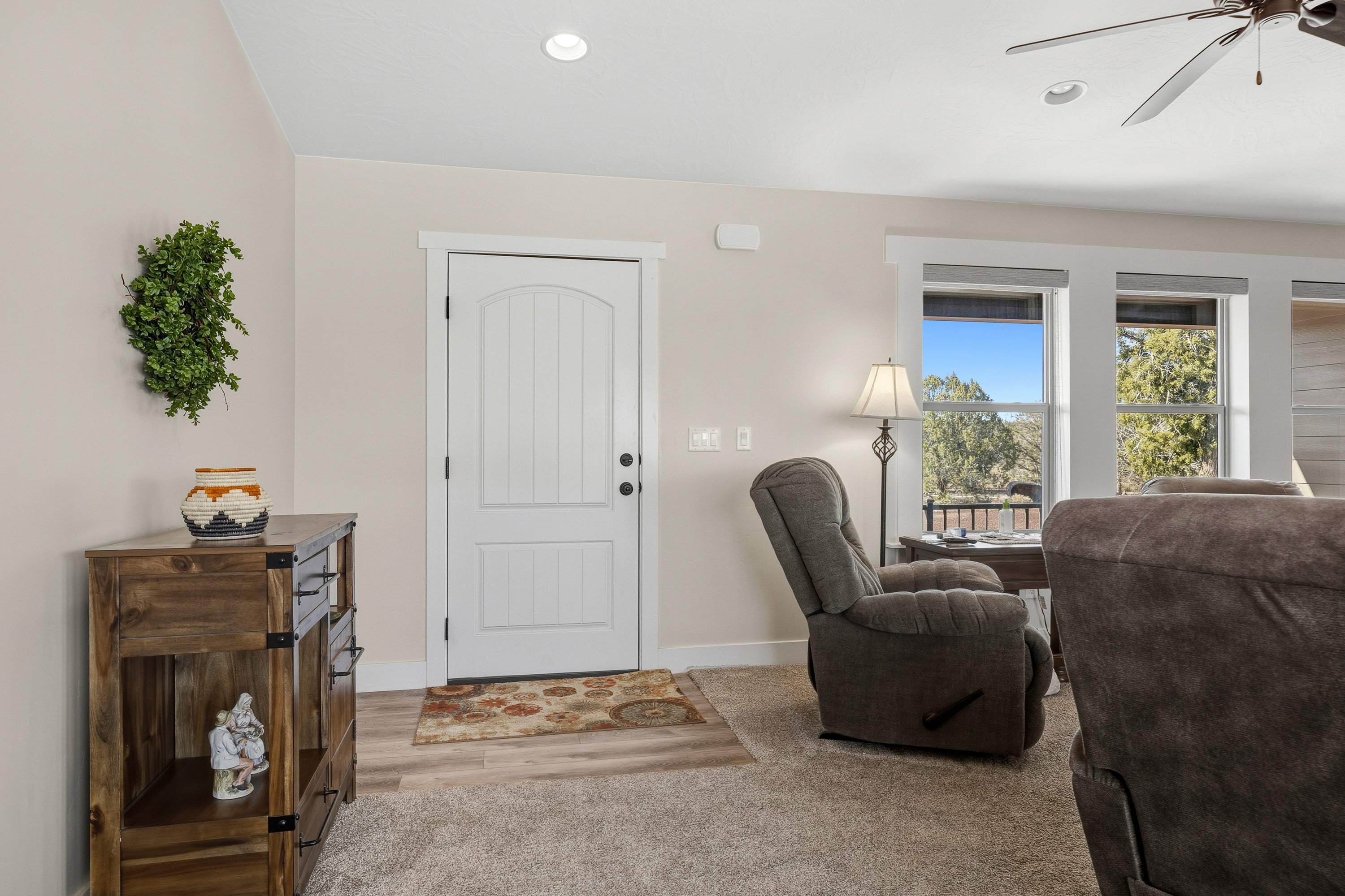 Entrance foyer with a ceiling fan and light carpet