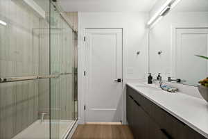 Full bath with vanity, light wood-type flooring, bath / shower combo with glass door, and a textured ceiling