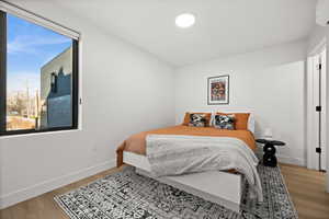 Bedroom with light wood-style flooring and a wall mounted AC