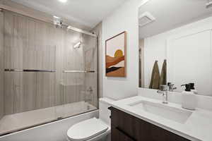 Full bath featuring vanity and bath / shower combo with glass door