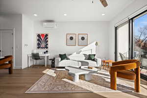 Living room with wood finished floors, recessed lighting, a ceiling fan, and a wall mounted air conditioner