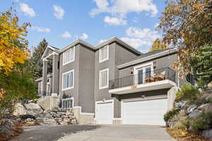View of front of house with a balcony, driveway, stucco siding, a garage, and stairs