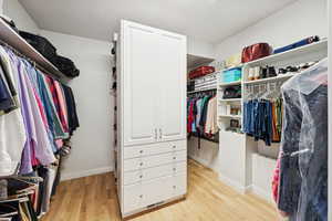 Walk in closet with light wood-type flooring