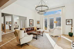 Living area with light wood finished floors, recessed lighting, a towering ceiling, and a chandelier