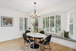 Dining space with light wood-type flooring and a chandelier