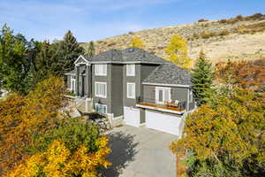 View of front of house featuring stucco siding, driveway, a garage, and roof with shingles