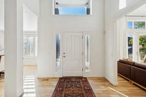 Entrance foyer featuring a towering ceiling, light wood-type flooring, and plenty of natural light