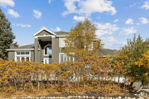 View of side of property with stucco siding, a chimney, and a shingled roof