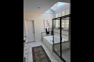 Bathroom with vanity, a whirlpool tub, a skylight, and healthy amount of natural light
