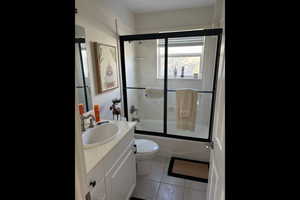 Bathroom with enclosed tub / shower combo, vanity, and light tile patterned floors