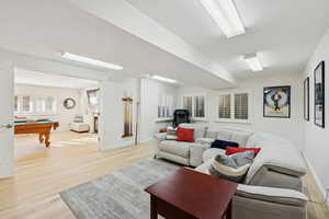 Living area featuring light wood finished floors, billiards table, and a fireplace