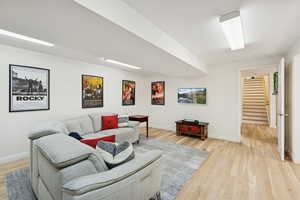 Living room with light wood finished floors and stairway