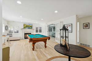 Rec room with pool table, light wood-style flooring, a fireplace with flush hearth, recessed lighting, and french doors