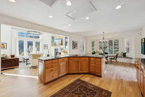 Kitchen featuring a chandelier, dark stone counters, light wood-style flooring, pendant lighting, and recessed lighting