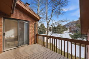 Snow covered deck with a mountain view and a balcony
