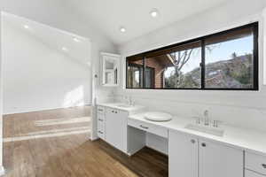 Full bath with double vanity, recessed lighting, vaulted ceiling, and light wood finished floors