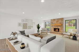 Living room with a fireplace, a textured ceiling, and recessed lighting