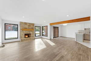 Unfurnished living room featuring a fireplace, light wood-style flooring, beamed ceiling, and recessed lighting