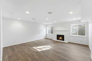 Unfurnished living room featuring a brick fireplace, wood finished floors, and recessed lighting