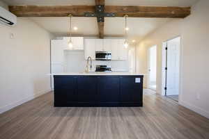 Kitchen featuring beamed ceiling, white cabinets, recessed lighting, dark cabinets, and decorative light fixtures