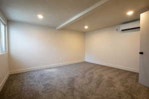 Spare room featuring dark carpet, recessed lighting, a wall mounted AC, and a textured ceiling