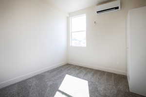 Carpeted empty room with a wall mounted AC and baseboards