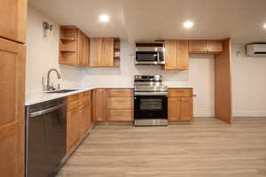 Kitchen with open shelves, recessed lighting, stainless steel appliances, light wood-type flooring, and light stone countertops