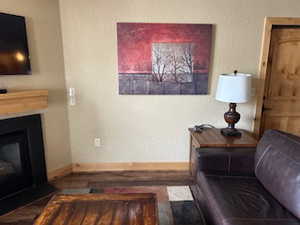 Living room with a textured wall, a glass covered fireplace, and wood finished floors