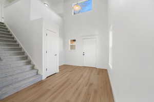 Foyer entrance with stairway, a high ceiling, and light wood-type flooring