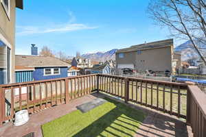 Wooden deck featuring a residential view, a mountain view, and a fenced backyard
