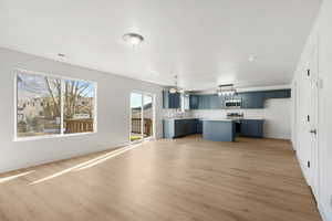Kitchen with blue cabinetry, light countertops, light wood-type flooring, a center island, and hanging light fixtures