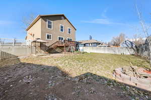 Rear view of property with a fenced backyard, stucco siding, stairway, and a deck
