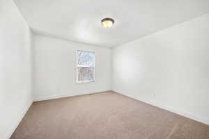 Empty room featuring light colored carpet and baseboards