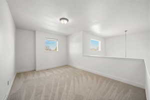 Empty room with light colored carpet and baseboards