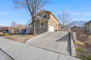 Traditional home with a mountain view, stucco siding, concrete driveway, a garage, and a residential view