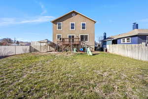 Rear view of house with a wooden deck, stucco siding, a fenced backyard, and stairs