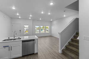 Kitchen with stainless steel dishwasher, white cabinetry, light wood-style flooring, recessed lighting, and open floor plan