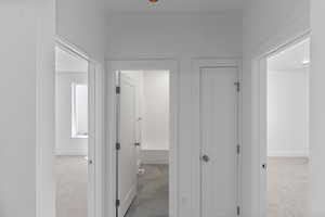 Corridor featuring light colored carpet and baseboards